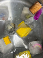 Ice cubes with various colorful objects inside a metal container